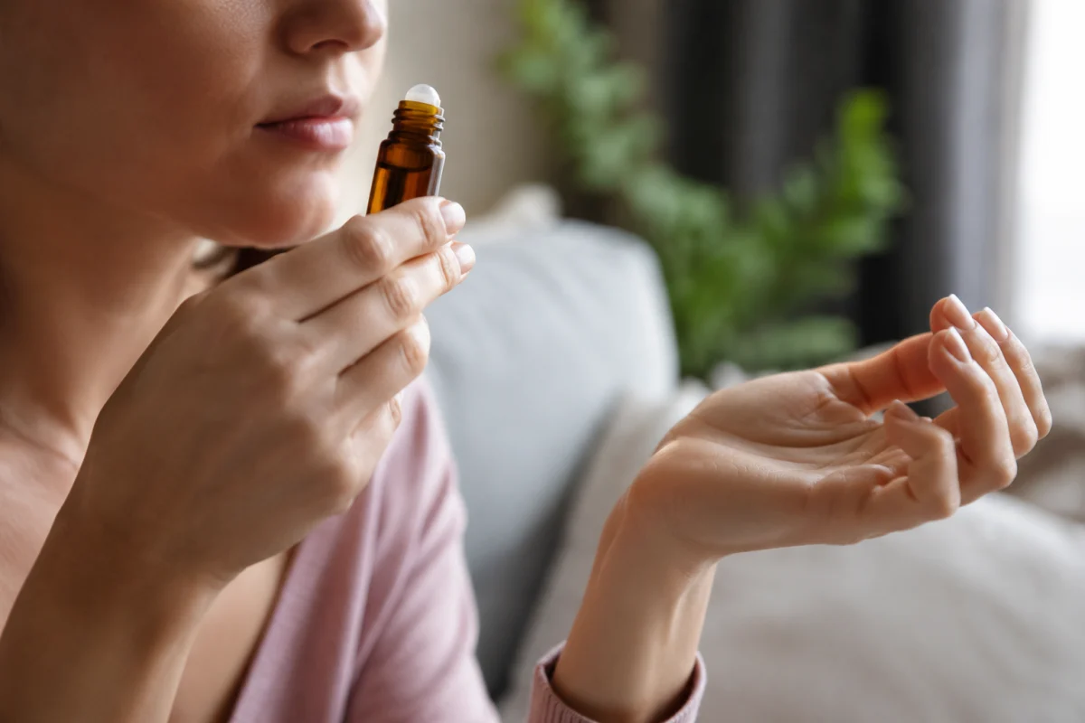 Quelle huile essentielle pour calmer une crise d'angoisse en urgence Main tenant un petit flacon d'huile essentielle de lavande ouvert, prête à être inhalée directement
