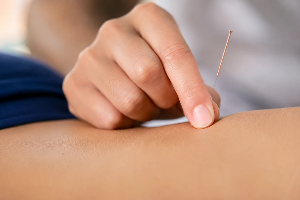 Acupuncture et acupression : laquelle choisir pour toi ? Gros plan sur des doigts exerçant une pression précise sur un point du poignet lors d'une séance d'acupression