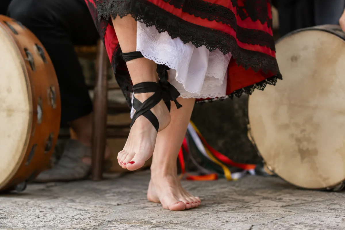L'histoire de la tarentelle, de la morsure à la transe sacrée Mains d'une musicienne frappant un tambourin à grelots lors d'une cérémonie de pizzica dans les Pouilles