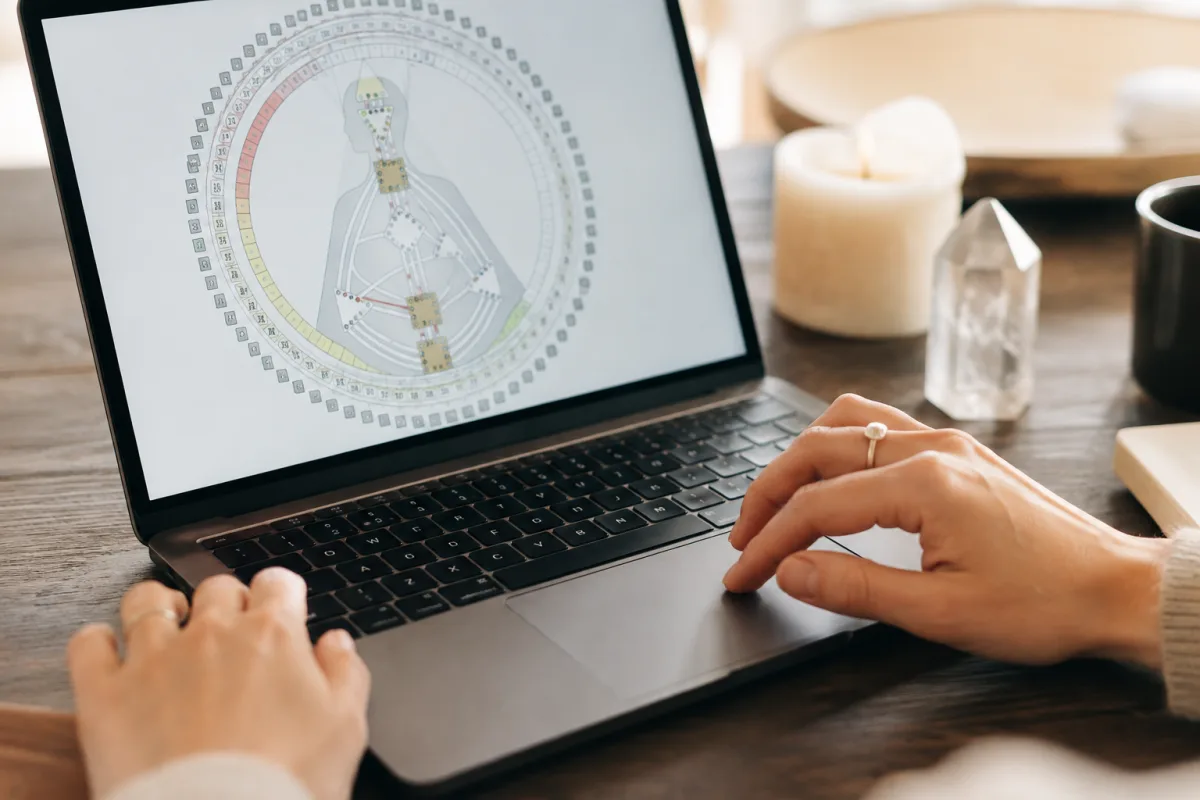 Faire son test de Human Design gratuit : ce que ta charte dit vraiment de toi Gros plan sur les mains d'une femme traçant les centres d'un bodygraph de Human Design sur du papier