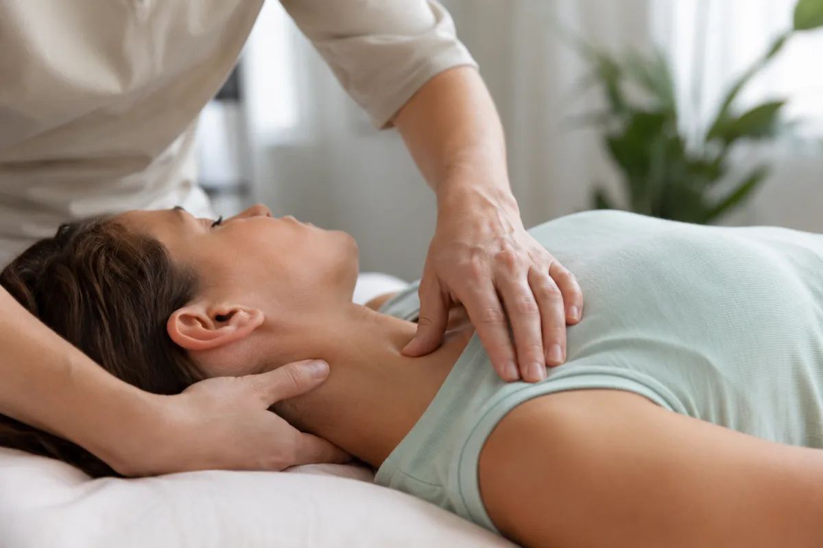 La somatopathie, c'est quoi ? Ce que ton corps garde en mémoire Gros plan sur les mains d'un somatopathe en contact léger avec la nuque d'un patient au repos