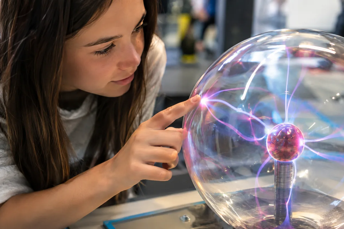 Ce que mes expériences au cœur de la science m'ont appris sur nous Gros plan sur les mains d'un visiteur touchant une sphère interactive lumineuse en expérience scientifique